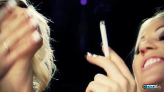 Wunderschöne blonde Mädchen, die sich gegenseitig die Beine reiben, während sie Zigaretten rauchen
